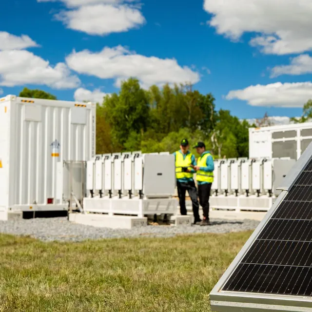 Battery storage containers on gravel with two greentech engineers between them