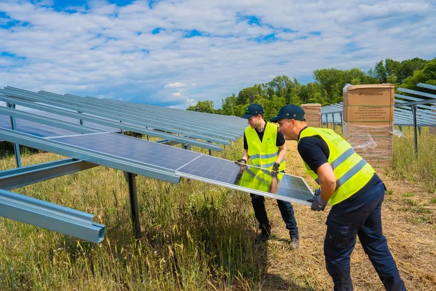 Two greentech installers mount a solar module on its frame