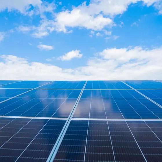 Solar modules under a blue sky with white clouds