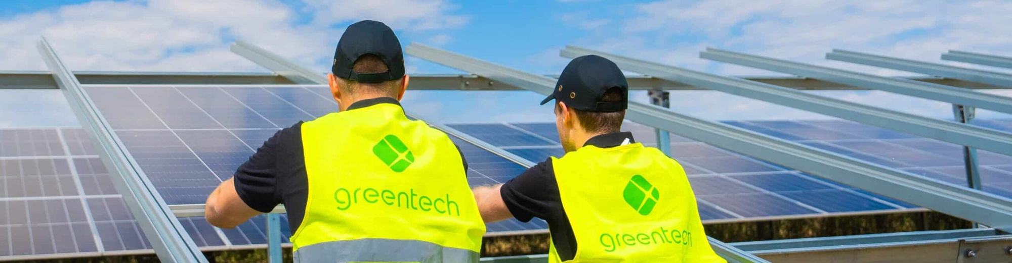 Two greentech colleagues in high-visibility vests with the greentech logo, working on a module table